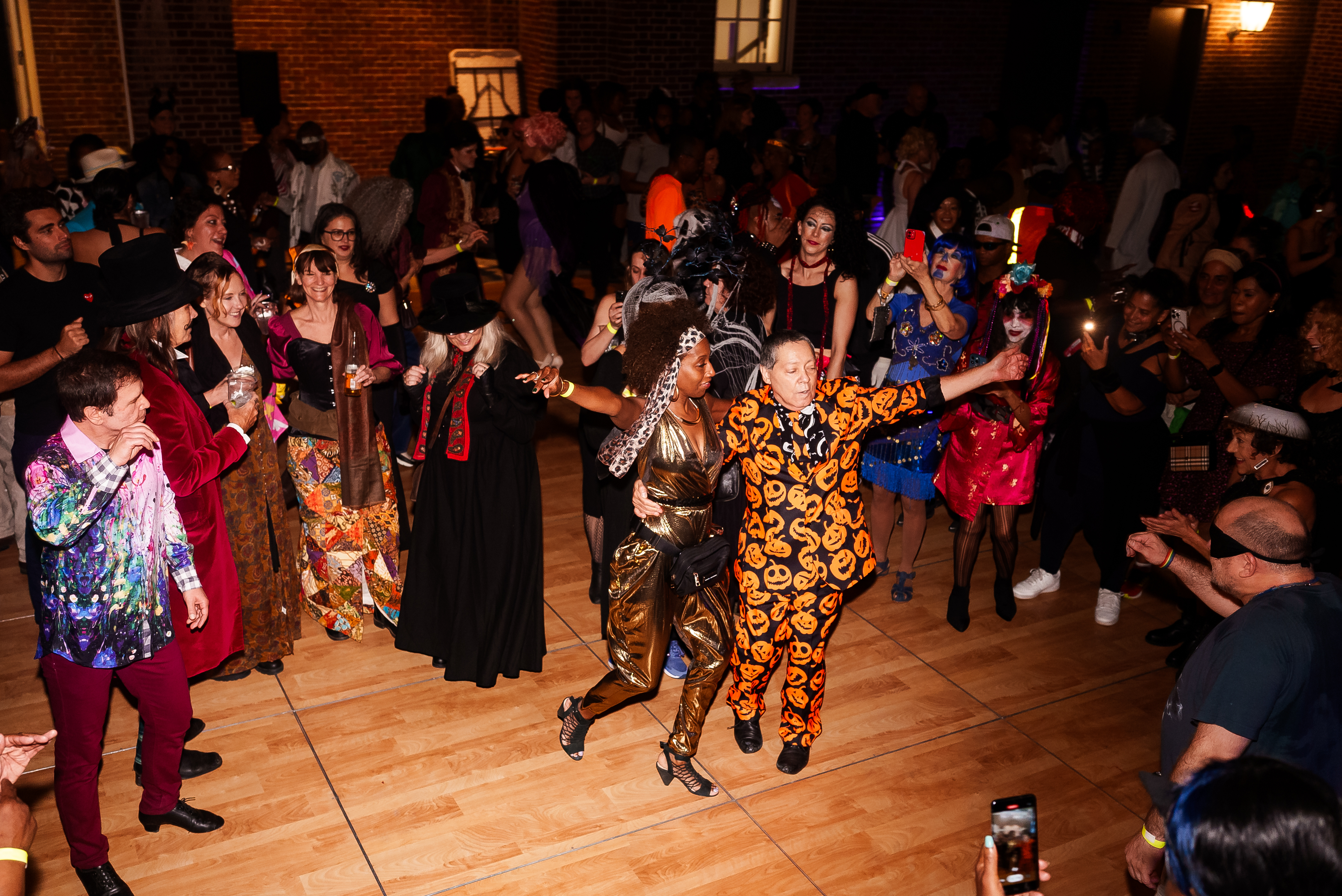 A lively crowd in colorful costumes enjoys dancing and celebrating at a Halloween party